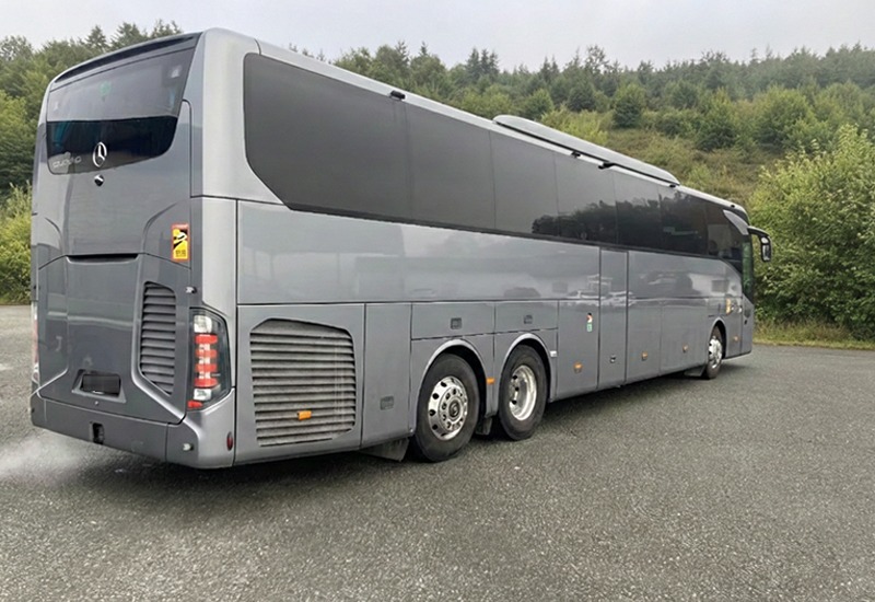 Silver three-axle Mercedes-Benz Tourismo coach, rear three-quarter view